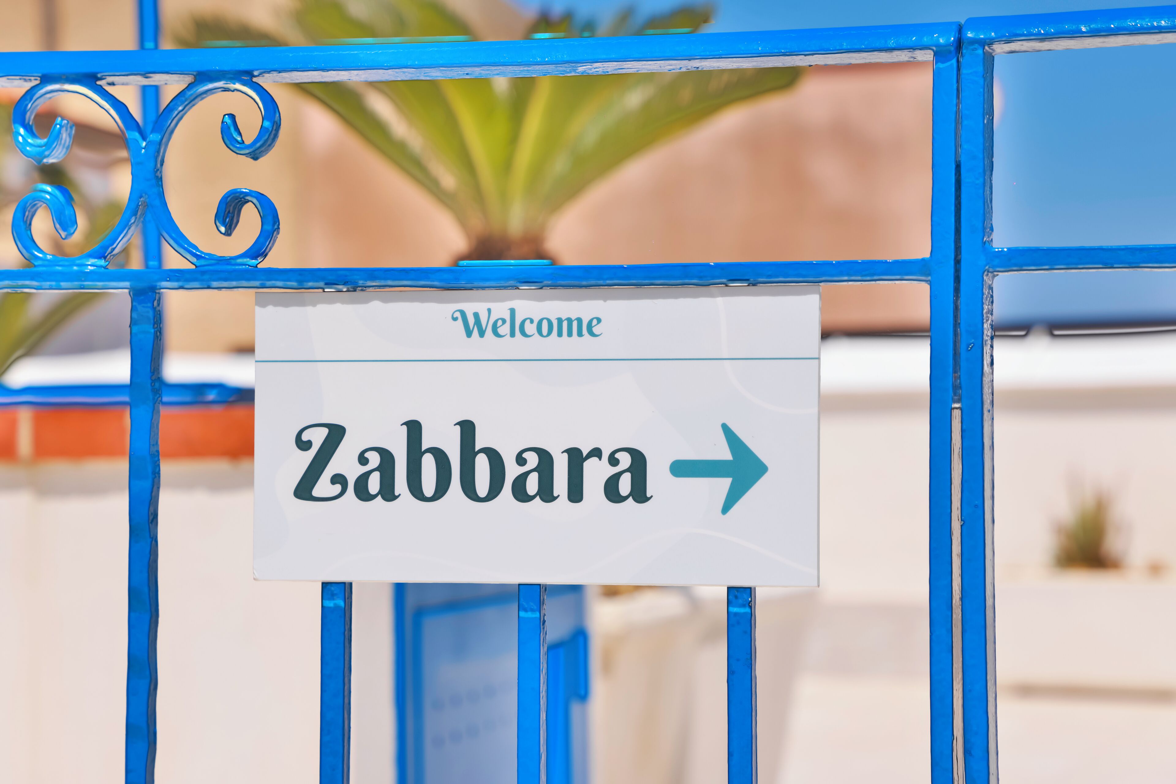 Placa com 'Bem-vindo Zabbara' e uma seta apontando para a direita.