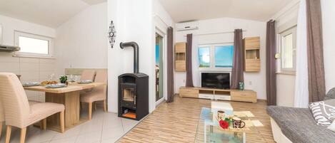 Ein modernes Wohnzimmer mit Kamin, Essbereich und einer Couch.