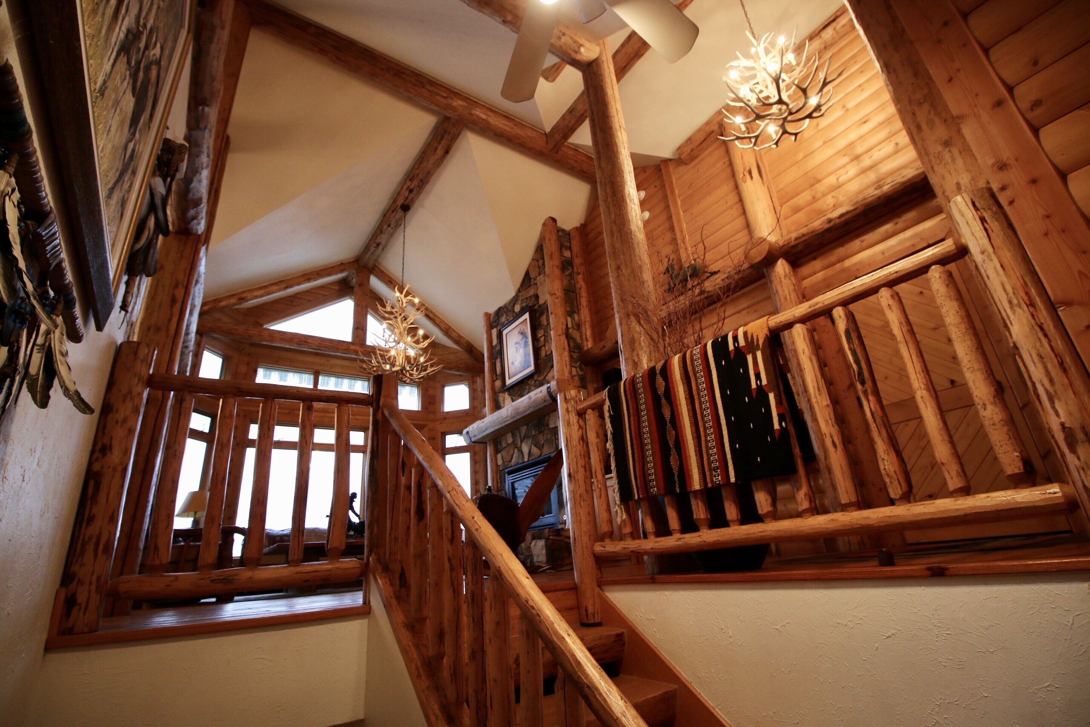 Una escalera de madera con candelabro, decoración rústica y pared de piedra.