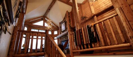 Una escalera de madera con candelabro, decoración rústica y pared de piedra.