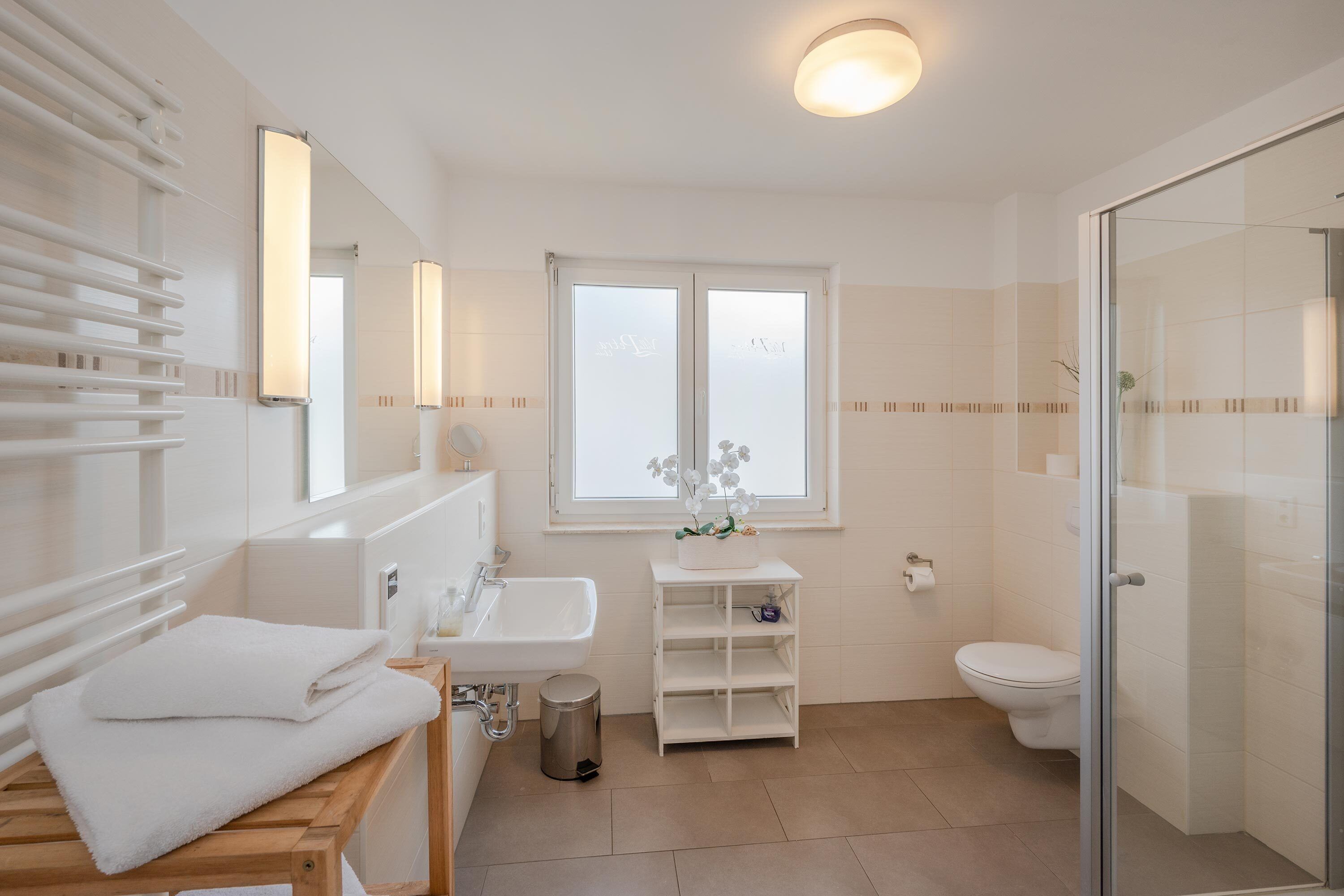 Een moderne badkamer met een douchecabine van glas, een witte wastafel en een toilet.