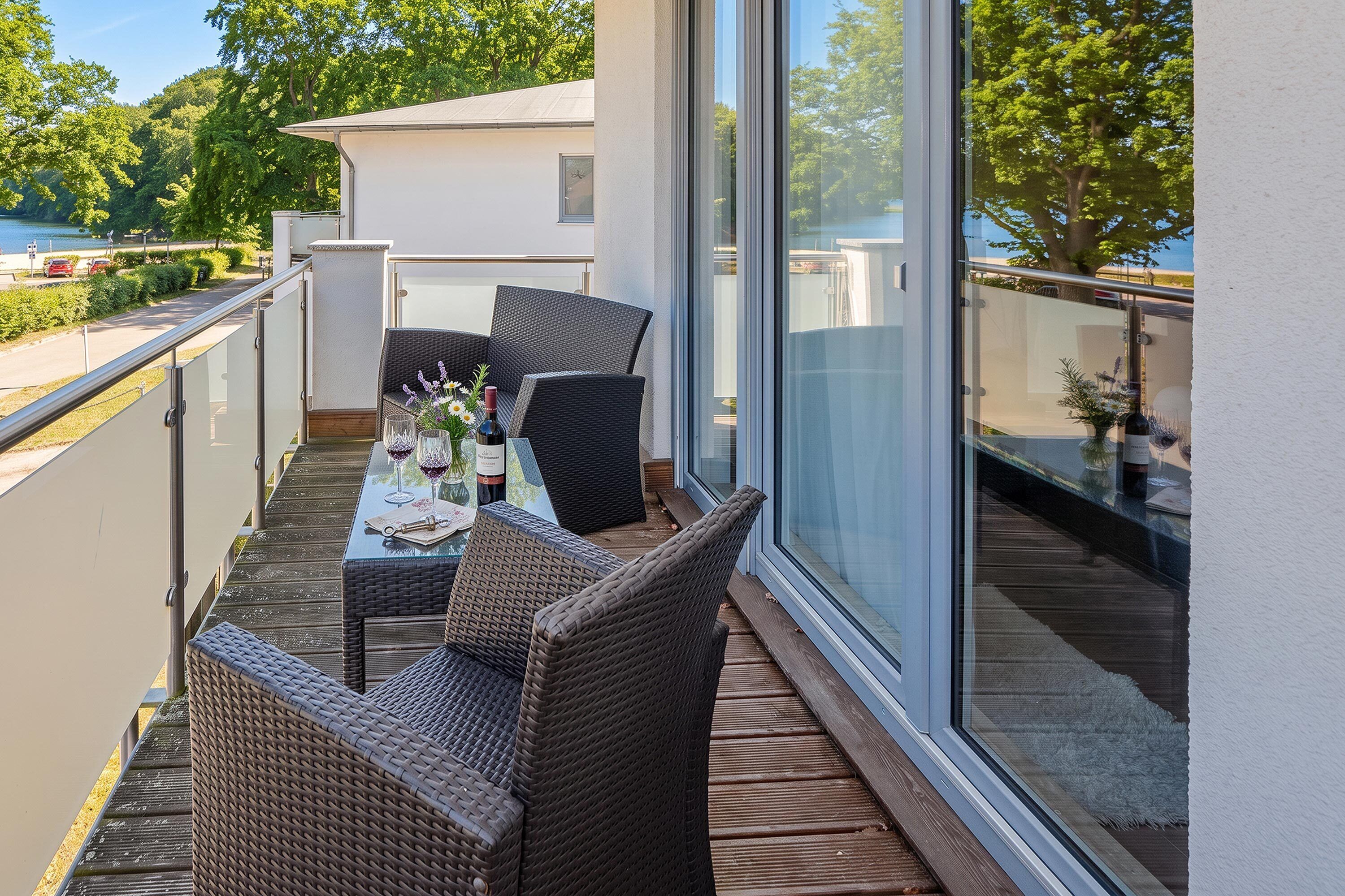 Ein Balkon mit Tisch für zwei Personen, Korbstühle und Blick auf einen See.