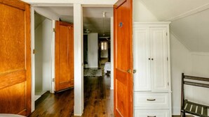A hallway with wooden doors leading to bedrooms, a white cabinet, and a bench. - The Avondale Attic (Chicago)