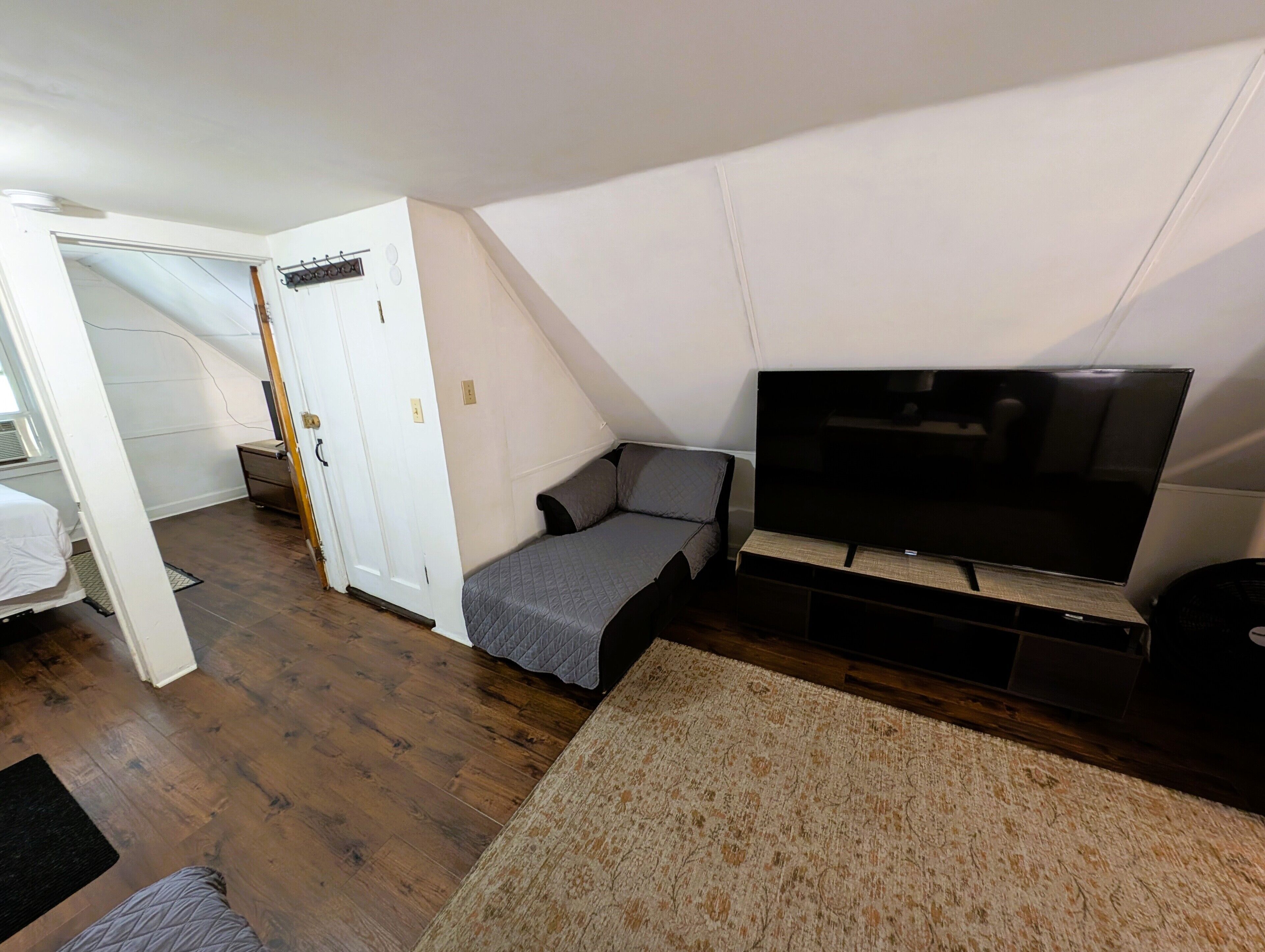 Une petite pièce bien éclairée, équipée d’un lit, d’une télévision et d’un bureau.