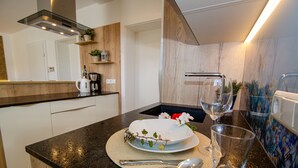 A modern kitchen with a black countertop, a white bowl with decorative flowers, a glass of water, and a spoon. - Apartment Nature & Friends - near Kaprun (Piesendorf)