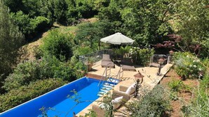 A swimming pool with a stone deck, surrounded by lush greenery and a patio area with outdoor furniture. - Charming country house in a quiet location with fantastic views and pool (Aramo)