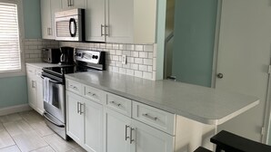 A modern kitchen with white cabinets, a microwave, a stove, and a toaster. - Beachside Townhouse: <br>Family Friendly & Renovated (Indian Harbour Beach)