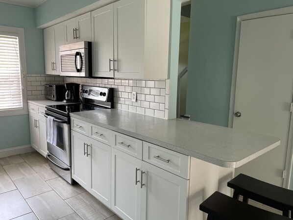 A modern kitchen with white cabinets, a microwave, a stove, and a toaster.