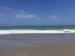 A beach with waves approaching the shore under a clear sky.