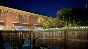 An outdoor patio with a wooden fence, two blue chairs, and a table. - Beachside Townhouse: <br>Family Friendly & Renovated (Indian Harbour Beach)