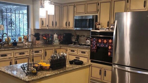 Una cocina con una isla central, electrodomésticos de acero inoxidable y un ventanal con ornamentos de hierro.