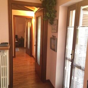 Un pasillo con pisos de madera, puertas de vidrio esmerilado y un radiador.