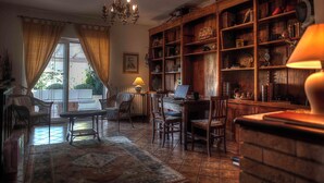 A cozy room with a wooden bookshelf, a desk with a laptop, wicker chairs, and a patterned rug. - Sarkeep - Villa Immersed in the vineyards of Taurasi (Luogosano (Avellino))