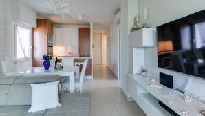 A modern living room with a sofa, TV, and a dining area with a table and chairs. - RICCIONE with BEACH and AQUAPARK INCLUDED /BEACH and AQUAPARK included !!! (Riccione)