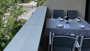 A balcony with a table set for dining, overlooking a street and a beach. - RICCIONE with BEACH and AQUAPARK INCLUDED /BEACH and AQUAPARK included !!! (Riccione)