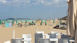 A beachside café with outdoor seating and umbrellas, overlooking the beach and distant hills. - RICCIONE with BEACH and AQUAPARK INCLUDED /BEACH and AQUAPARK included !!! (Riccione)