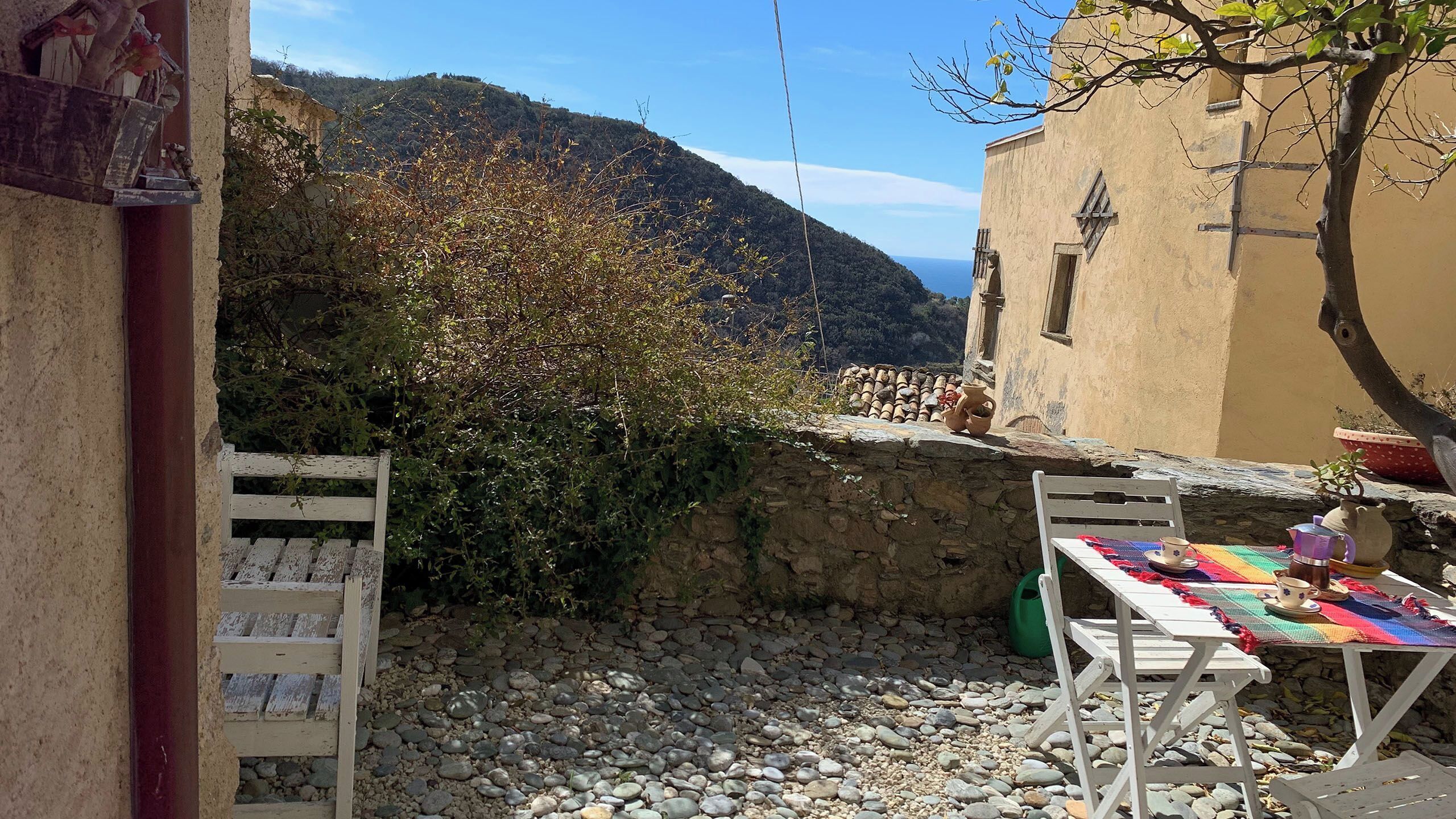 A rustic outdoor seating area with a stone wall, wooden benches, and a table set for a meal.