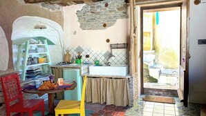 Une cuisine rustique avec un mur en pierre, un évier et une table en bois entourée de chaises.