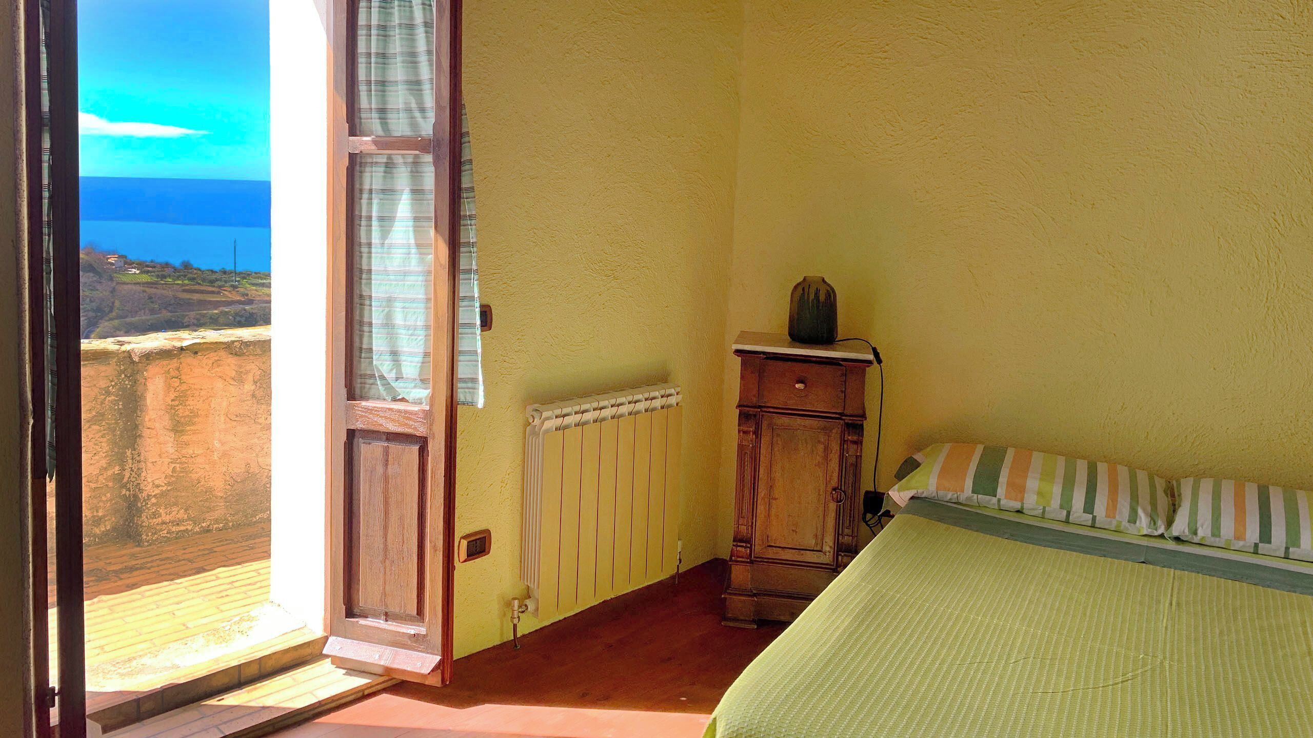 Una habitación con cama, un armario de madera, un radiador y una ventana con cortinas.