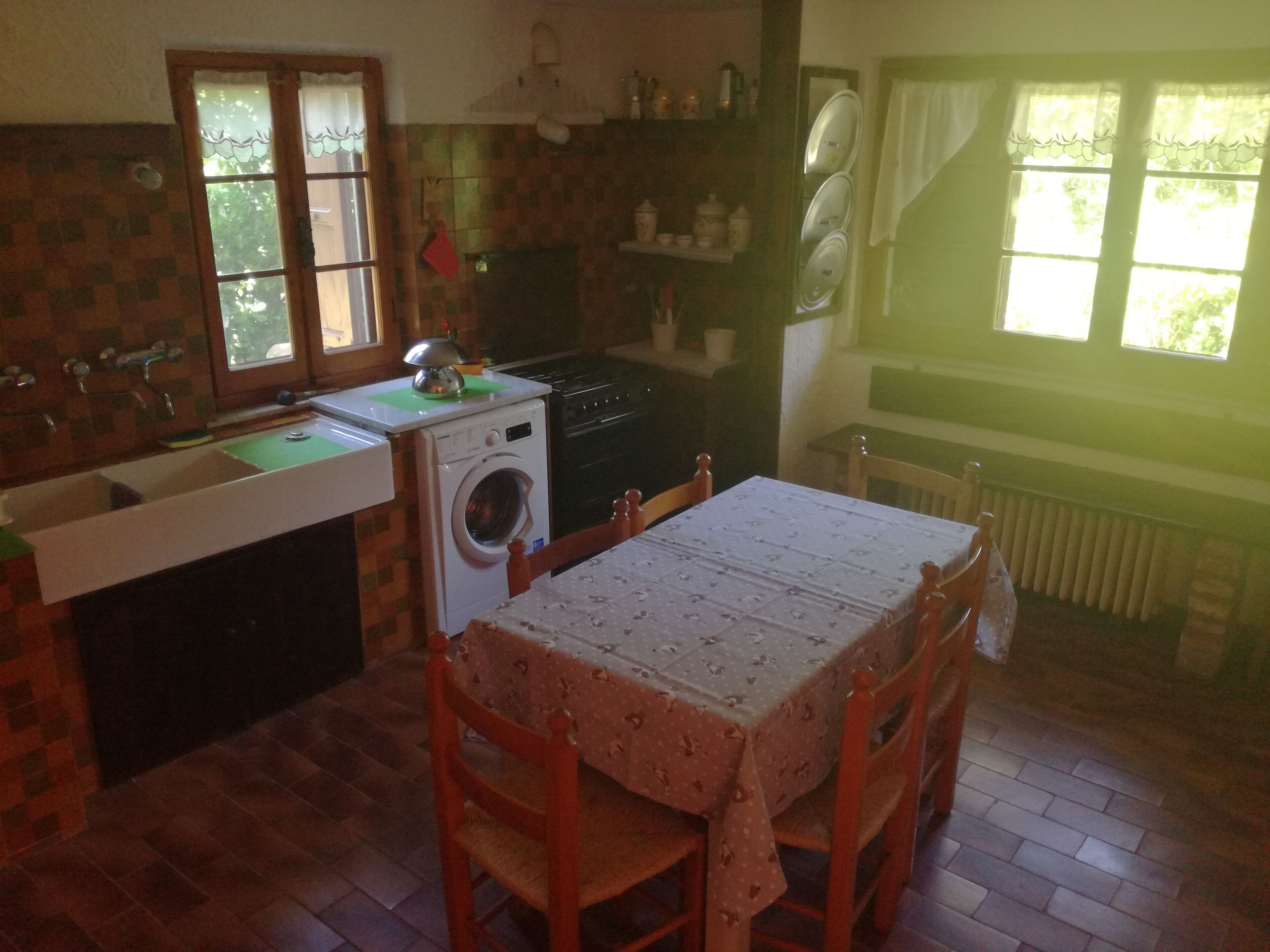 Eine Küche mit Waschmaschine, Spüle und Tisch mit Stühlen.