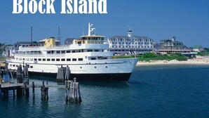 Et stort, hvidt krydstogtskib ligger ved kaj, med en bygning i baggrunden.