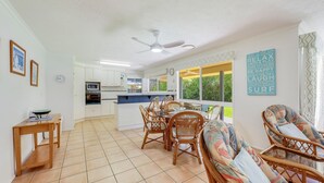 A spacious living area with a kitchen, dining table, and chairs. - 22 Bussey Street Bargara (BARGARA)