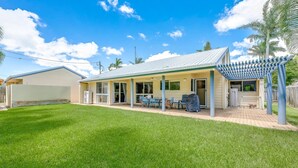 A single-story house with a covered patio area, a fenced yard, and a clear blue sky. - 22 Bussey Street Bargara (BARGARA)