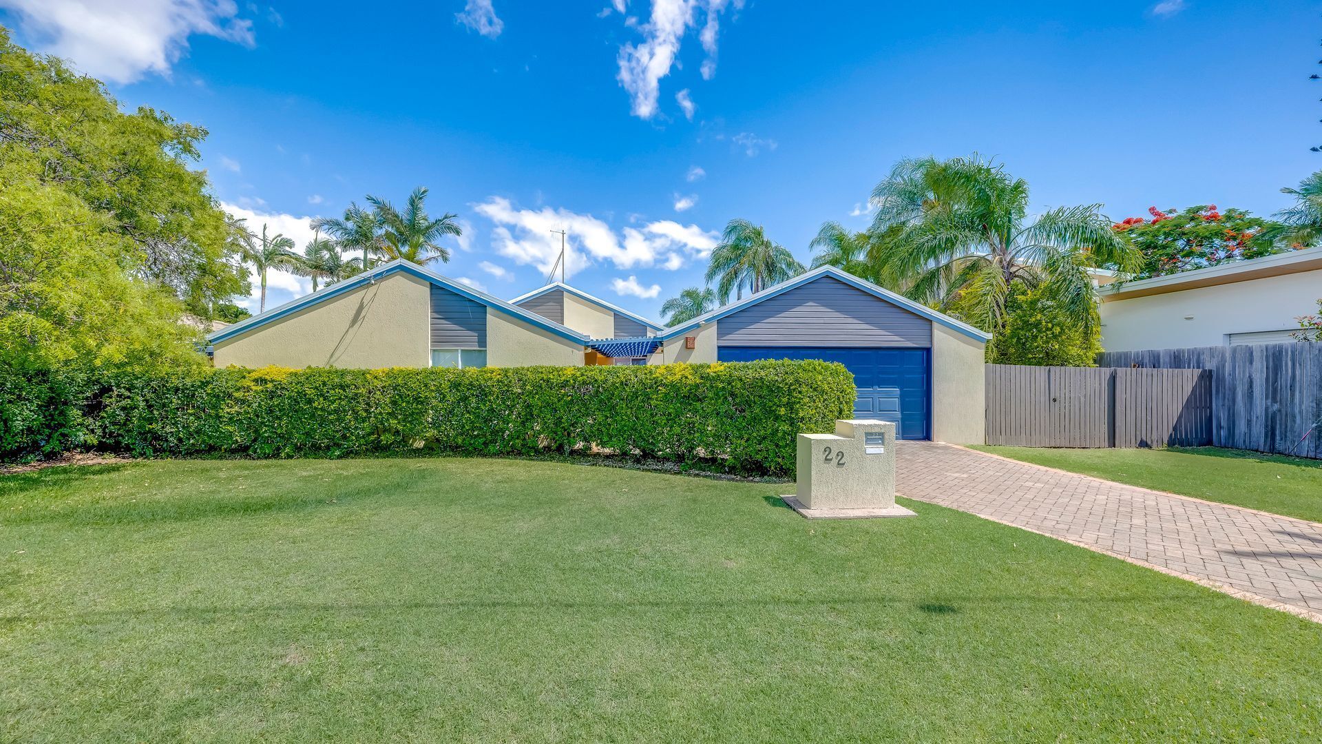 A residential property with a well-maintained lawn, a driveway leading to a garage, and a number '22' mailbox.