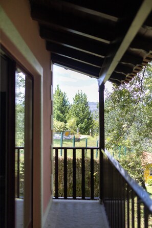 A balcony with a view of a garden and trees.