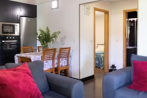 Un espace de vie compact comprenant une kitchenette, un coin repas et une chambre.