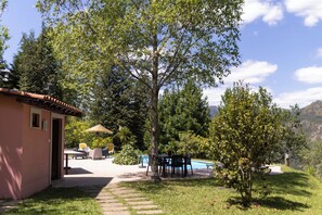 Un patio con mobili da esterno, una piscina e un edificio con tetto in tegole.