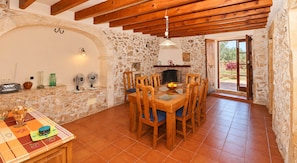 A rustic dining area with a stone wall, wooden ceiling beams, and a tiled floor. - Can Cova 413 rustic finca with private pool, terrace, air conditioning and WiFi (Es Llombards)