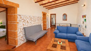 A living room with a stone wall, a grey sofa, a blue sofa, and a wooden coffee table.