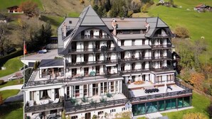 A large, multi-story building with a swimming pool, surrounded by lush greenery and hills. - Luxury 3 Bed apartment,  panoramic mountain views,  5* Spa Facilities - (La Soldanelle)