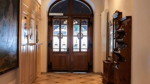 A hallway with a double wooden door with glass panels, a tiled floor, and a wooden cabinet on the right. - Luxury 3 Bed apartment,  panoramic mountain views,  5* Spa Facilities - (La Soldanelle)