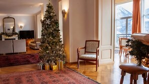 A cozy living room with a large Christmas tree, a fireplace, and a view of mountains through the window. - Luxury 3 Bed apartment,  panoramic mountain views,  5* Spa Facilities - (La Soldanelle)