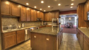 A kitchen with wooden cabinets, granite countertops, stainless steel appliances, and recessed ceiling lights.