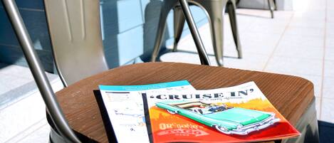 Una silla con una revista encima, un cartel que indica la habitación 2 y un anuncio publicitario de un crucero.