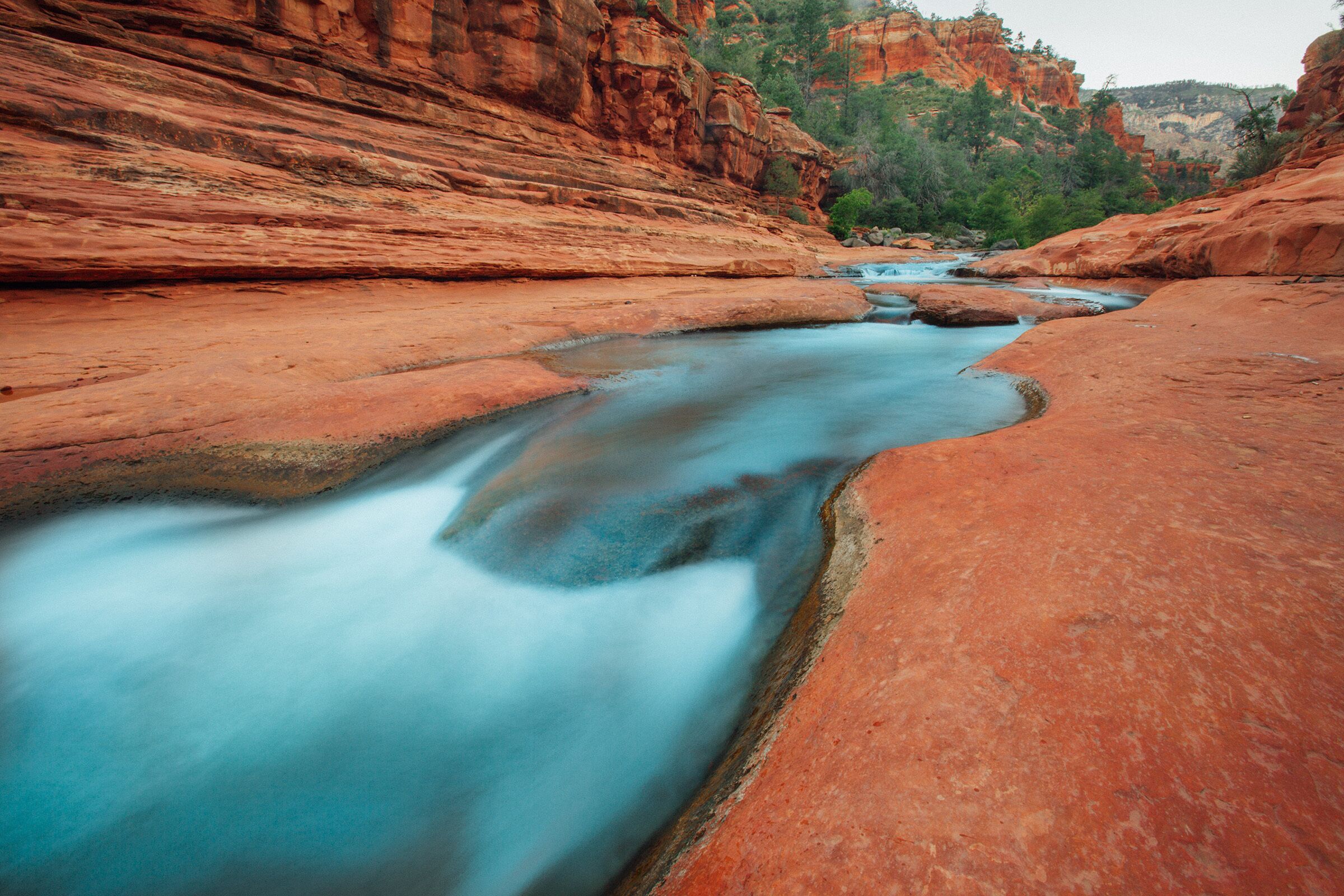 A river flowing through a canyon with red rock formations.