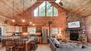 Ein geräumiges Blockhaus mit Küche, Essbereich und Kamin aus Stein.