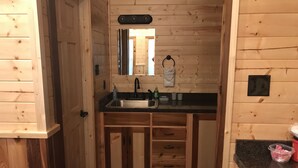 Interior de uma cabana de madeira com cozinha, incluindo pia, bancada e armários.