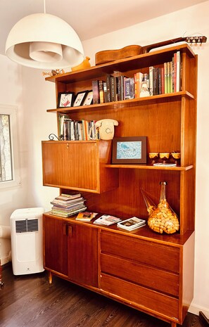 Una estantería de madera con varios estantes, un teléfono antiguo y un florero con flores.