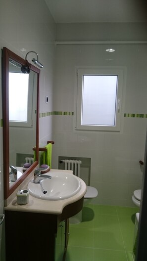 A bathroom with a white sink, mirror, and green-tiled floor.