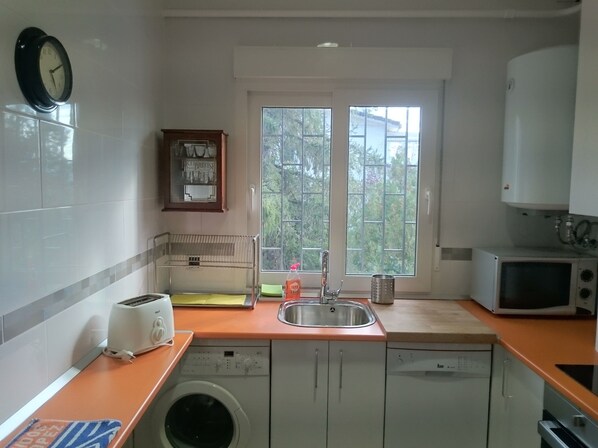 A compact kitchen with a washing machine, a sink, a microwave, and a toaster.