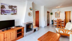 A living room with a fireplace, television, wooden furniture, and a dining area with chairs and a table. - FRANCESC MACIA 57 3B  Roses (Rosas / Roses)