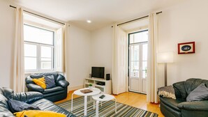 Een moderne woonkamer met een zwarte leren bank, een witte salontafel en een gestreept vloerkleed.