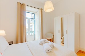 Relax in this serene hotel room featuring a comfortable bed, a stylish chair, and a wardrobe.