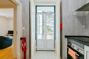 A hallway with a double door, a fire extinguisher, and a kitchen area with a stove and oven. - Balcony & Dream View 3BR Historic District Apartment by Rent4Rest (Lisboa ciudad)