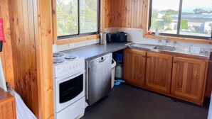 Une cuisine de taille réduite avec des murs en bois, une cuisinière, un lave-vaisselle et un évier.