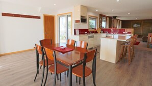 A modern kitchen with a central island, wooden dining table with chairs, and a cozy living area with a sofa and a coffee table. - Love Shack - Location and views this property has it all (Robe)
